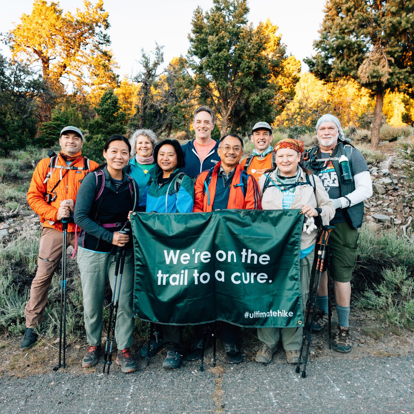 Ultimate Hike participants on the Pacific Crest Trail hold up a large banner that reads 'We're on the trail to a cure".